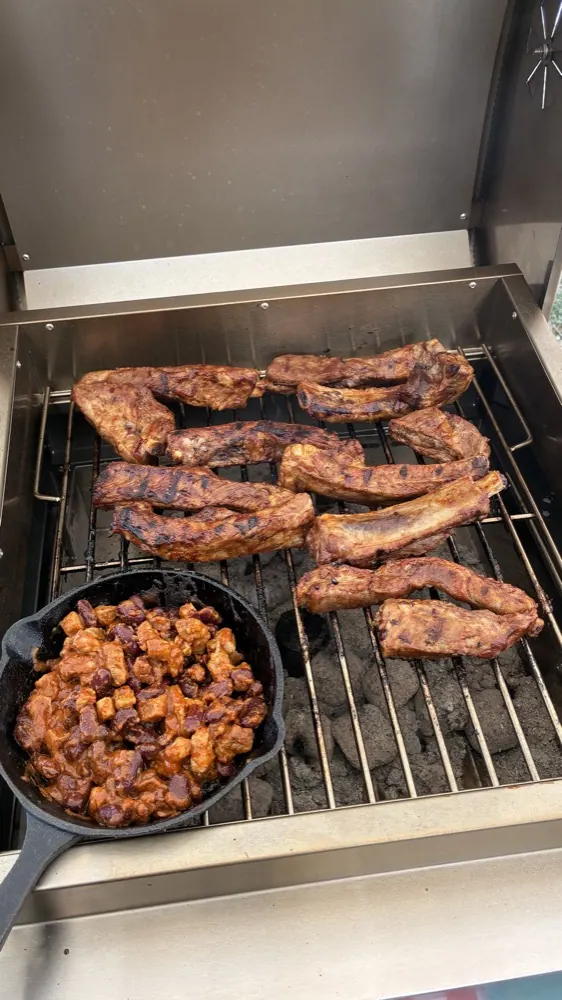 グリルで焼いている、骨付きの肉とチリビーンズ